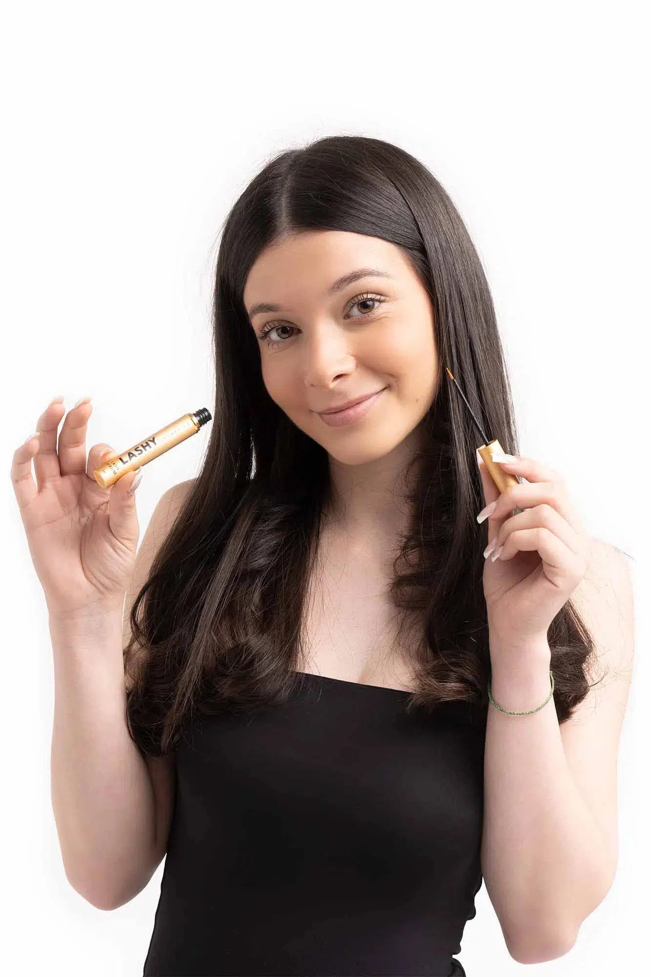 Half-body view of a smiling Lashy Cosmetics model holding a bottle of Lashy eyelash serum with clear Lashy branding visible.