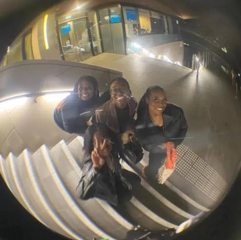 Group of joyful friends reflected in a convex mirror during a night out, showcasing their natural beauty enhanced by using Lashy's eyelash growth serum.